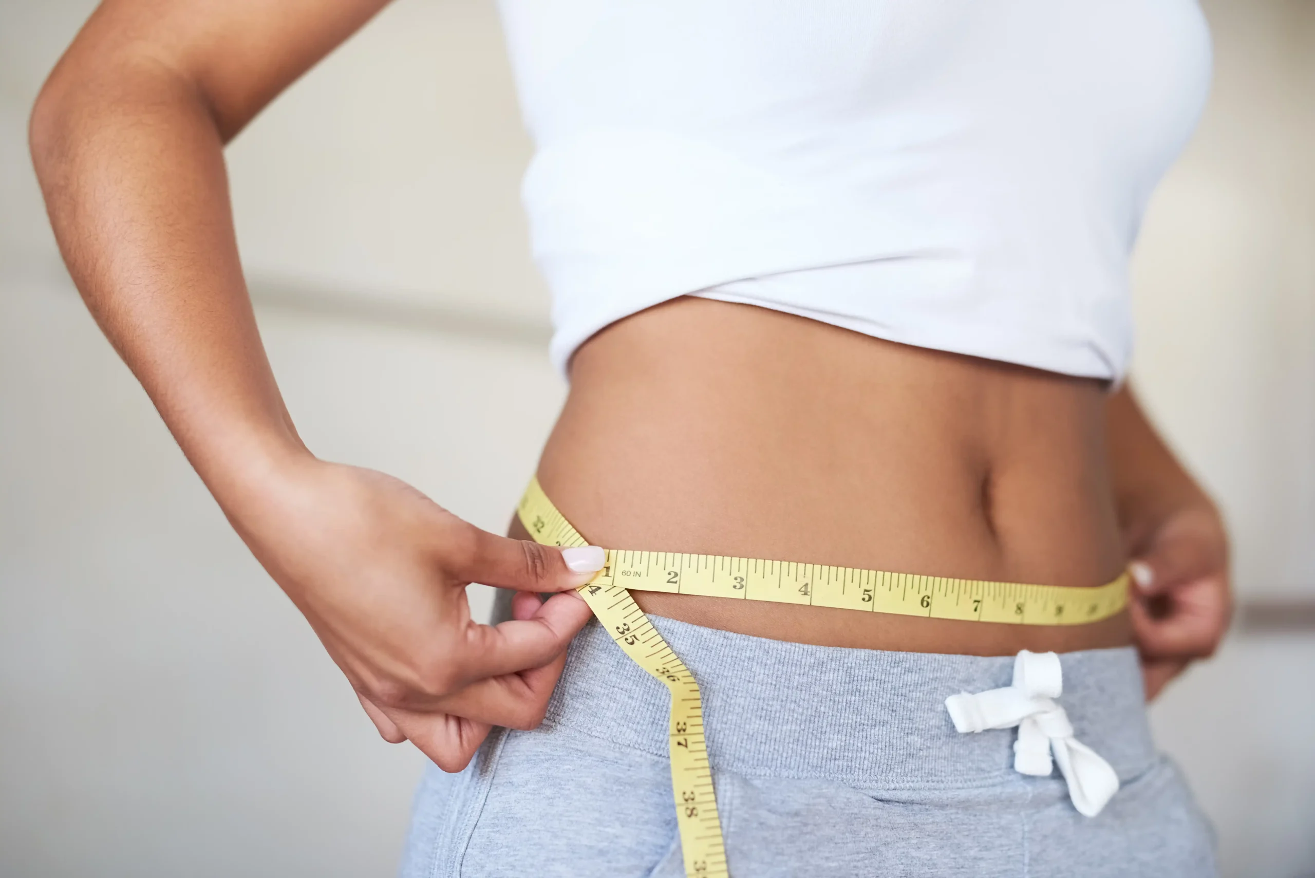Säure-Basen-Haushalt: Bild einer Frau mit flachem Bauch und einem Maßband herum nach Entschlackung, was zur Gewichtsabnahme führt